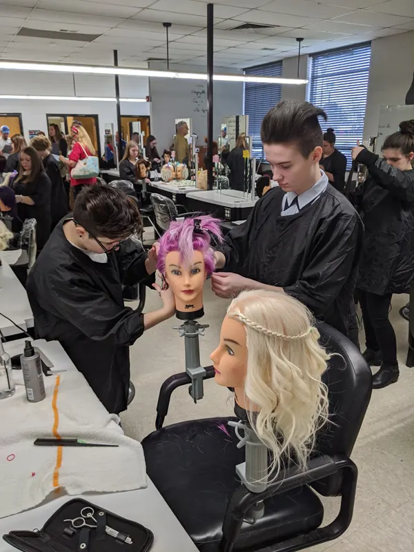 Students practicing hair styling on mannequin heads