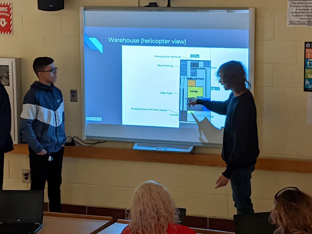 Two students speaking while pointing at projection screen
