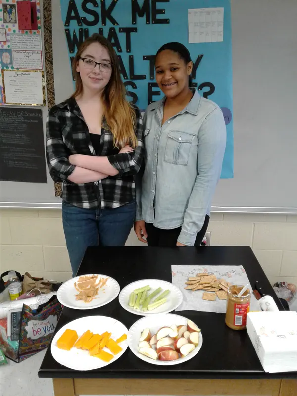 Two students standing in front of lunch table