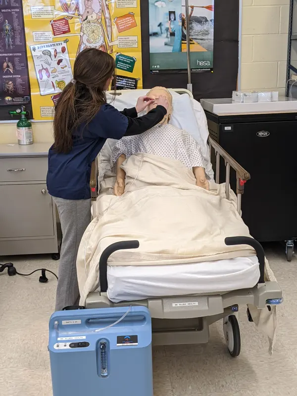 Student practices putting nose tube on dummy